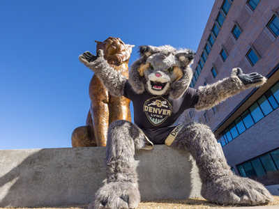 Milo the mascot sitting with the Milo the Lynx Statue
